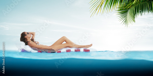 View of nice young girl is hanging on air mattress in tropic environment