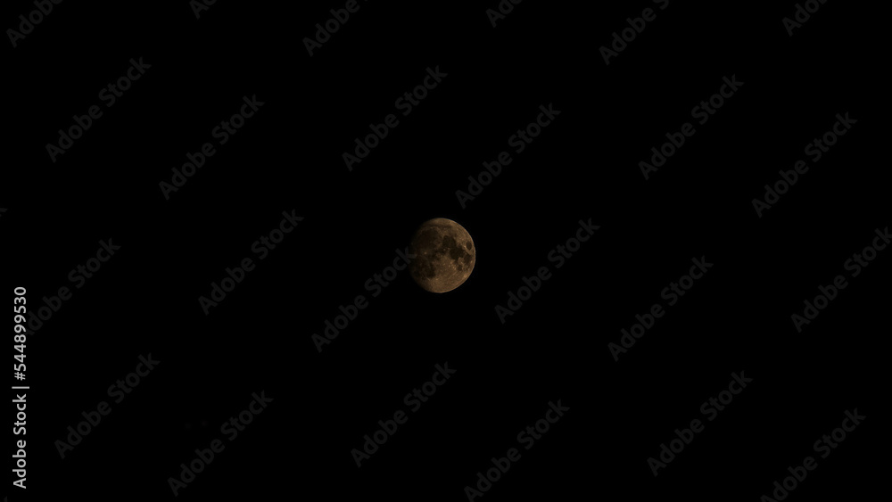 image of an incomplete lunar disk in the night sky.