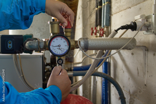 Image of the hands of a plumber who opens a hot water tap of a boiler. First ignition of a boiler in anticipation of winter
