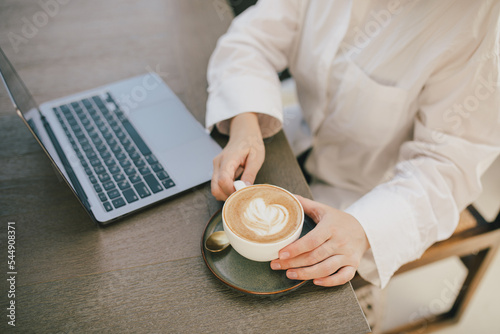 Young woman with laptop and a cup of coffee.