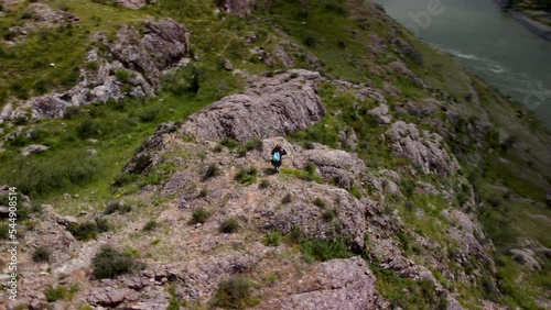 A traveler walks through the hills and takes photos and videos of the spectacular scenery.
Panoramic drone footage of a mountain landscape and traveler exploring a new hiking trails.