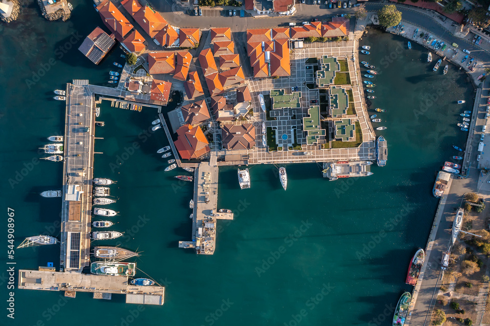 Aerial view of Nessebar, an ancient town on the Bulgarian Black Sea coast with red-roofed houses and piers with yachts and small boats amid turquoise waters