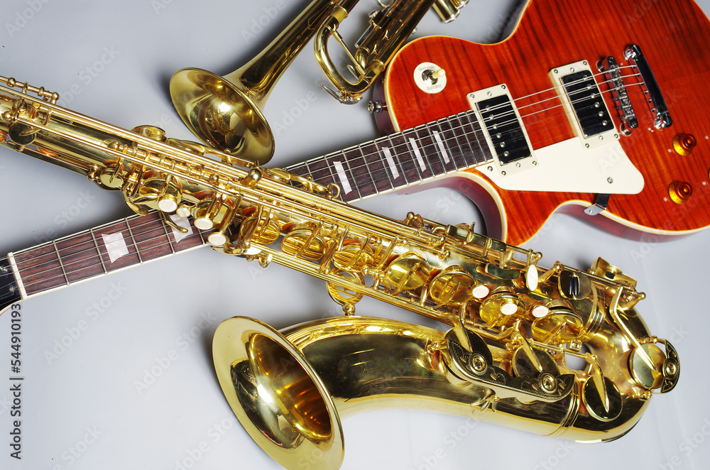 Obraz premium Electric guitar, trumpet and golden saxophone on a light background.
