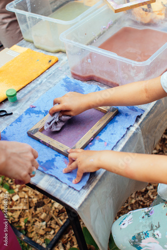 close-up children's hands wipe the water with a rag. Master class on making handmade paper. do it yourself lesson teacher helps student. DIY totorial