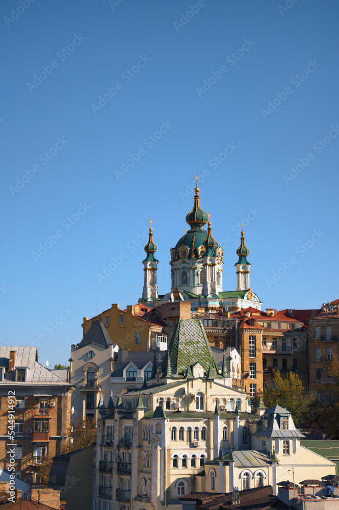Picturesque autumn cityscape of Kyiv. Saint Andrew's Church and ancient buildings of Andrew's Descent (Andriyivsky uzviz, Podil neighborhood). Famous touristic place and romantic travel destination