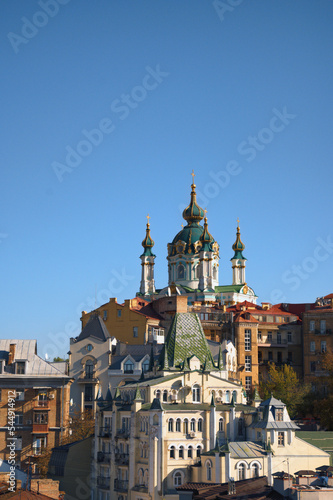 Picturesque autumn cityscape of Kyiv. Saint Andrew's Church and ancient buildings of Andrew's Descent (Andriyivsky uzviz, Podil neighborhood). Famous touristic place and romantic travel destination