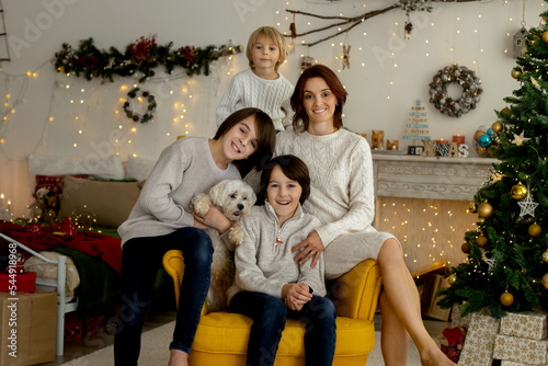 Happy family with three kids and dog, sitting at home at Christmas, cozy atmosphere © Tomsickova