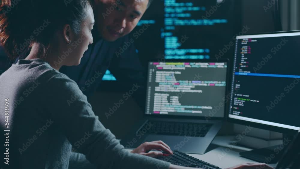 Young Asian woman, developer programmer, software engineer, IT support, with colleague working hard at night overtime on computer to check coding in bugging system together
