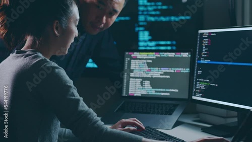 Young Asian woman, developer programmer, software engineer, IT support, with colleague working hard at night overtime on computer to check coding in bugging system together