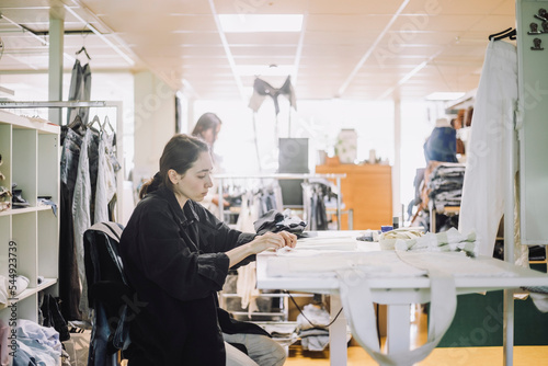 Side view of female fashion designer working at workshop