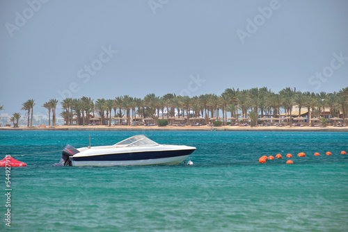 Seascape with ripple surface of blue sea water with white speedboat on anchor floating on calm waves © bilanol
