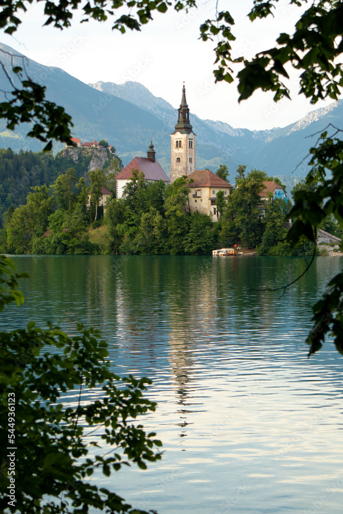 Lake Bled Island, framed by leaves. Slovenia. Summer morning by the waterside. Lake Bled Island, framed by leaves. Slovenia. Summer morning by the waterside.