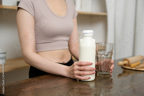 An Asian young woman in sportswear drinking milk in kitchen at home , healthy lifestyle concept