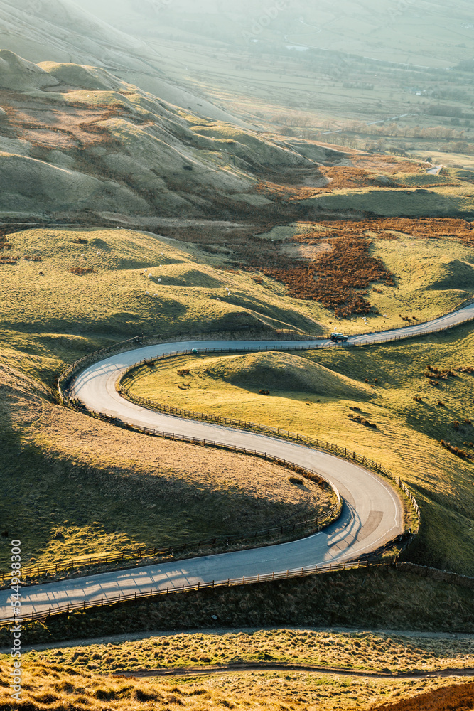 Winding road bathed in sunlight. Rolling Green hills. The road to Edale, Peak District Uk. 