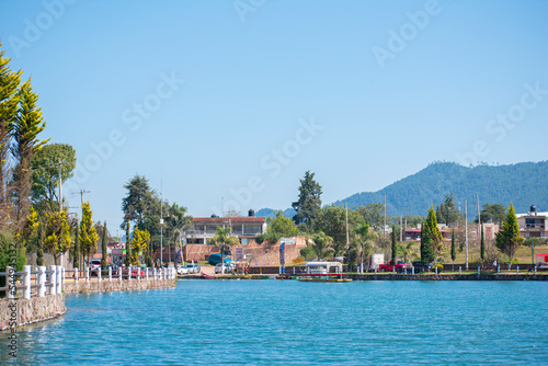 tropical landscape view with mountains, trees, blue sky, cars and cal water