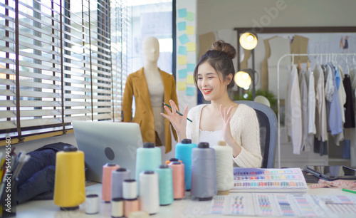 Portrait of freelance designer, tailor, stylist artist Asian woman, Thai person working, talking video call conference webcam online on fashion clothes, shirts at home. People lifestyle. business.
