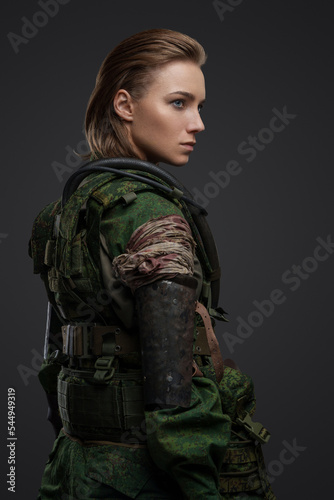 Shot of military woman with brown hairs and gas mask dressed in camouflage costume.