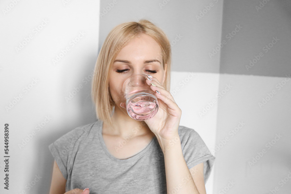 Blonde girl drinks water in the kitchen. Glass of water in the morning. Drink water after workout Blonde girl drinks water in the kitchen. Glass of water in the morning. Drink water after workout