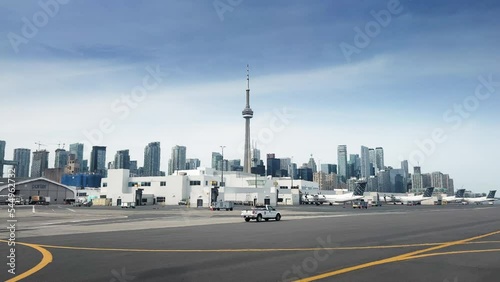 CN tower with modern high rise buildings viewed from airport against blue sky