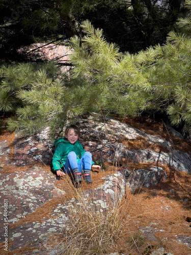 Boy sitting on rock under tree shadow in forest