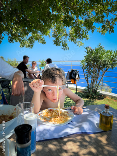 Boy eating spaghetti at outdoor restaurant