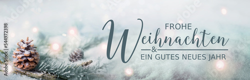 Christmas greeting card German text - Frohe Weihnachten und ein gutes neues Jahr - Pine cones and fir branches in winter snow landscape with magic lights in background -  Panorama, banner.