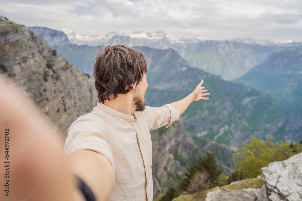 Man tourist on background of Breathtaking panoramic view of the Grlo Sokolovo gorge in Montenegro. In the foreground is a mountain, the flat side of which forms a cliff, and the ridge is overgrown