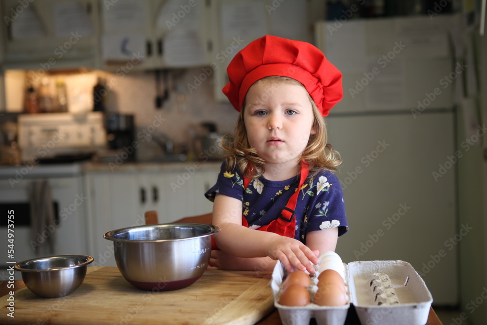 A Beautiful Little Girl, already a chef, cooking and demonstrating how to crack eggs in a home kitchen A Beautiful Little Girl, already a chef, cooking and demonstrating how to crack eggs in a home kitchen