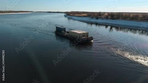 River tow pusher with barge. Clip. Top view of barge floating with cargo on river. River barge pusher picturesquely floats on background of horizon on sunny day photo