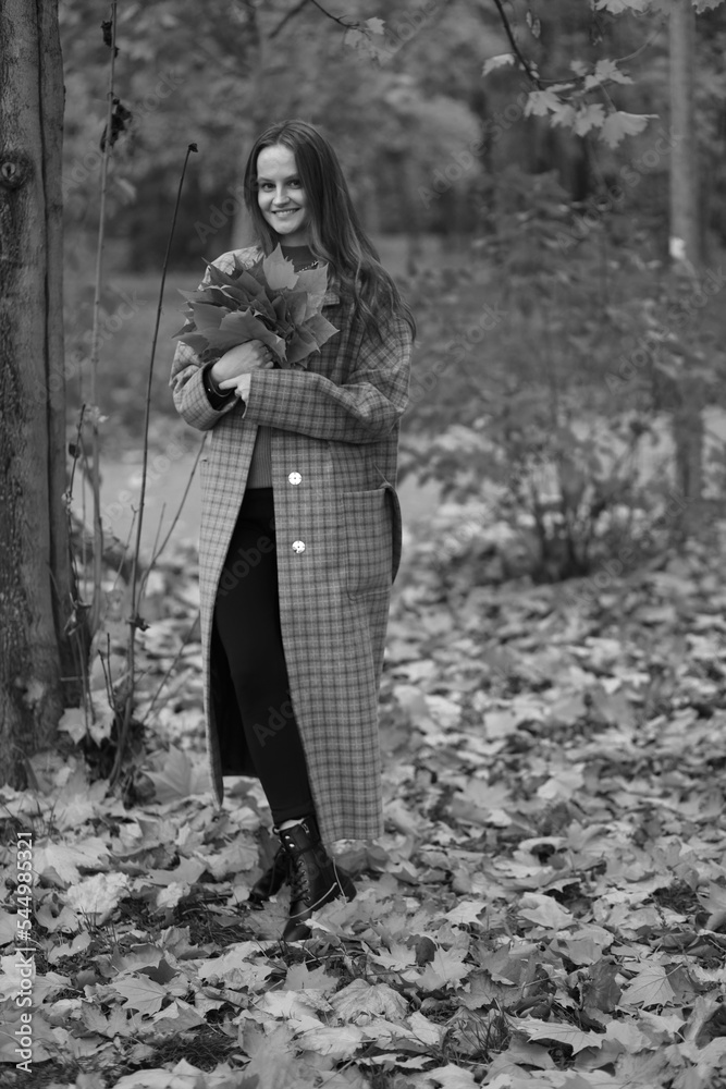 Young woman collecting autumn leaves in black and white