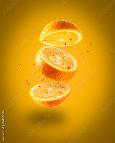 Flying juicy orange on an orange background. Isolated object on background. A splash of orange juice. Ripe juicy yellow orange.