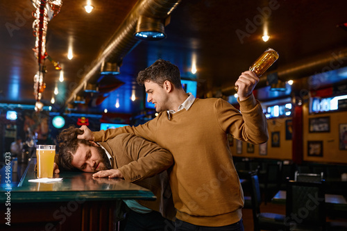 Soccer fans fighting at sport bar, guy attacks friend photo