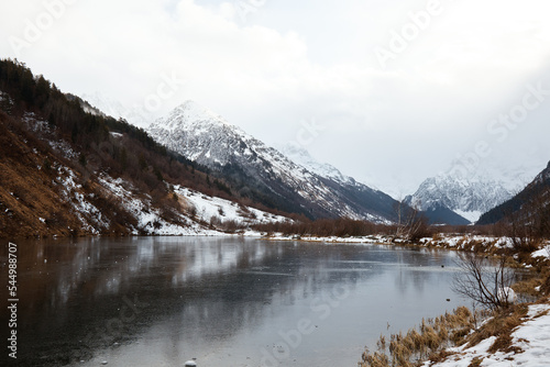 Fototapeta Naklejka Na Ścianę i Meble -  winter mountain lake in snow, in background of mountain, landscape pond with ice on water