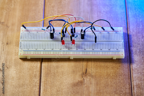Breadboard with electrical elements, on a wooden table.