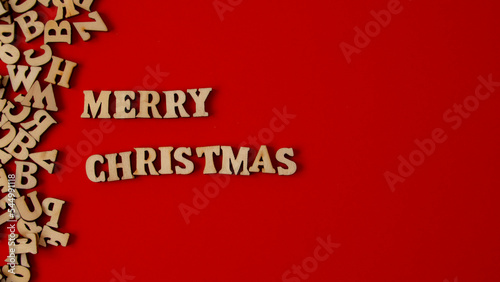 Wooden letters on a deep red background written in English "Merry Christmas"