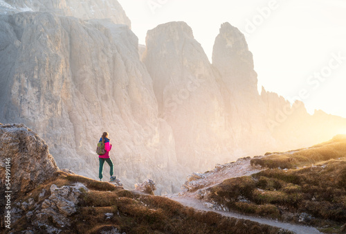 Canvas-taulu Young woman with backpack on the mountain trail and mountain canyon at sunset