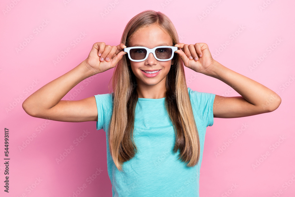 Photo of cheerful sweet small kid wear turquoise t-shirt arms dark spectacles smiling isolated pink color background Photo of cheerful sweet small kid wear turquoise t-shirt arms dark spectacles smiling isolated pink color background