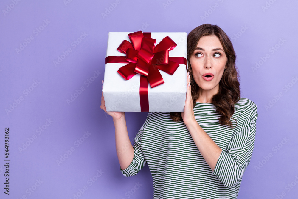 Photo of astonished lovely girlfriend lady hand hold present box listen interested look empty space isolated on purple color background Photo of astonished lovely girlfriend lady hand hold present box listen interested look empty space isolated on purple color background