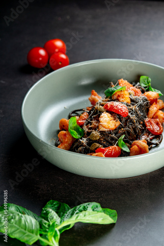 black paste with cuttlefish ink basil ad tomato on blavk background