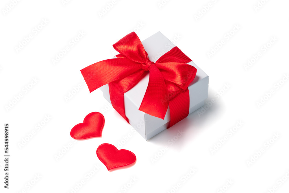 Composition of white gift box decorated with a red bow and two satin hearts, isolated on white background Composition of white gift box decorated with a red bow and two satin hearts, isolated on white background