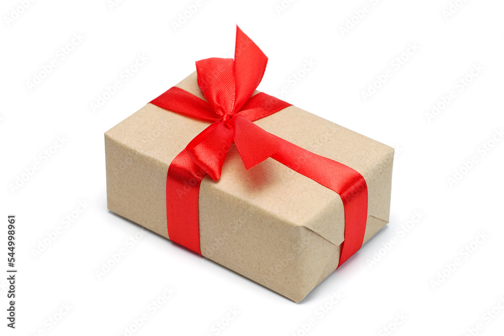 Obraz premium Close up shot of gift box wrapped in craft paper and decorated with red satin ribbon bow, isolated on white background
