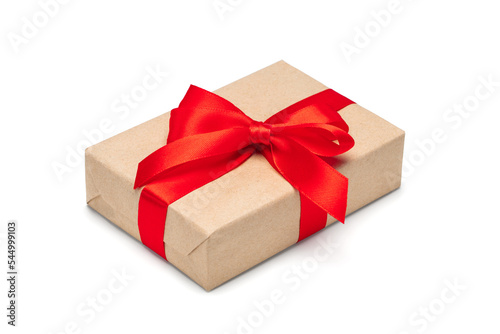 Fototapeta Naklejka Na Ścianę i Meble -  Close up shot of gift box wrapped in craft paper and decorated with red satin ribbon, isolated on white background