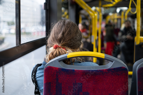 The back of the head of a girl with curly hair on a tram