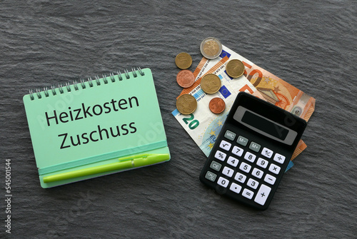 Das Wort Heizkostenzuschuss auf einem Notizblock mit Taschenrechner und Euro Banknoten.