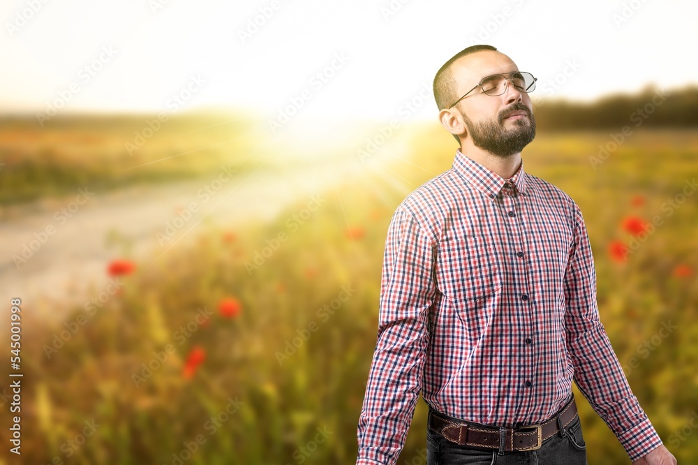 Happy young person praying on field background