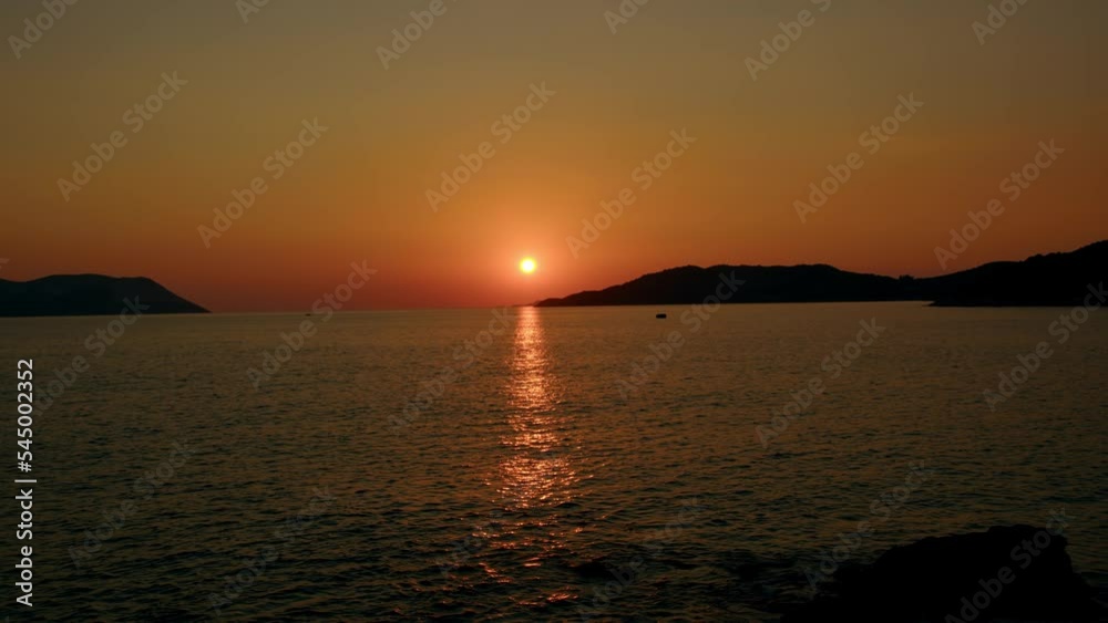 Fiery red sunset over sea between mountains in sea or ocean. Picturesque sunrise with sunny path on water. concept of end of career or its beginning. Natural phenomenon in morning. Fiery red sunset over sea between mountains in sea or ocean. Picturesque sunrise with sunny path on water. concept of end of career or its beginning. Natural phenomenon in morning.