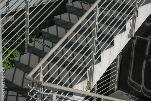 staircase architecture: detail of the external access stairs to the floors, with concrete steps, while the railing and handrail are in white painted steel.
