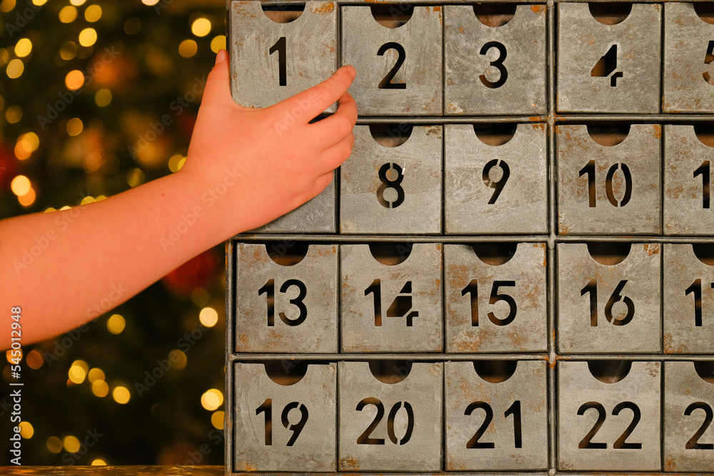 metallic-advent-calendar-in-vintage-style-and-childs-hand-near