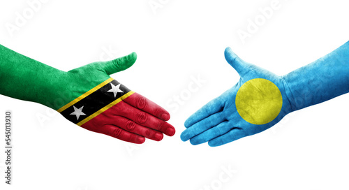 Handshake between Palau and Saint Kitts and Nevis flags painted on hands, isolated transparent image.