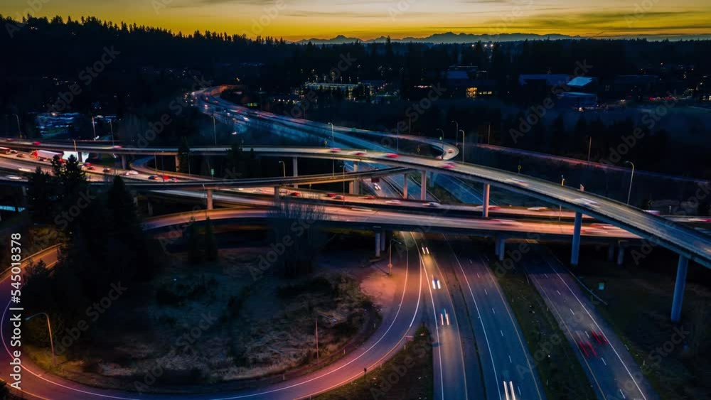 Aerial hyperlapse of a busy and interesting freeway interchange at sunset with mountains in the background.